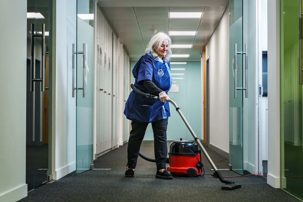 ACS office cleaner vacuuming communal hallway