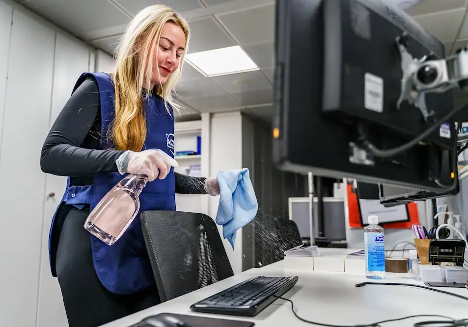 ACS office cleaner cleaning office desks with spray and cloth